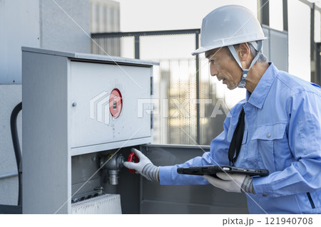 屋外消火栓設備の点検をする作業服の男性　ビルメンテナンス　イメージ 121940708