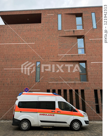 Ambulance next to a large brick walled building 121942313