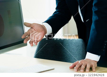 パソコンの前で説明するビジネスマン パソコンの前で説明するビジネスマン 121942428