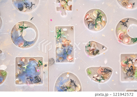 Creative resin art with colorful shells and decorative elements in mold shapes Creative resin art with colorful shells and decorative elements in mold shapes 121942572