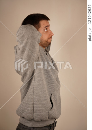 Crossed hands over head. Young male standing in front of camera. Man looking at camera. Man in casual clothes with neutral background. A handsome guy. Crossed hands over head. Young male standing in front of camera. Man looking at camera. Man in casual clothes with neutral background. A handsome guy. 121942626