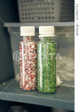 Colorful bead containers with red and green beads in clear plastic bottles 121942751