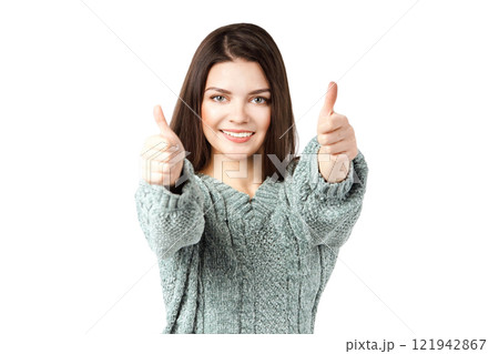 Smiling caucasian female young adult giving thumbs up gesture in cozy sweater 121942867