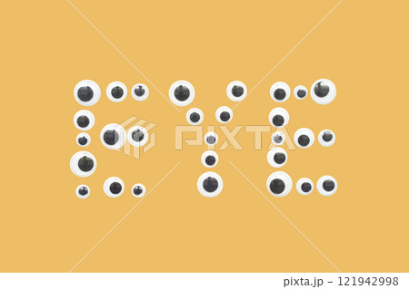 Googly eyes forming the word eye on a yellow background 121942998