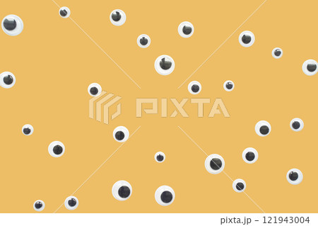 Scattered googly eyes on yellow background with playful and creative design 121943004