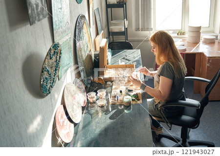Caucasian female adult artist creating unique ceramic designs in a bright studio Caucasian female adult artist creating unique ceramic designs in a bright studio 121943027