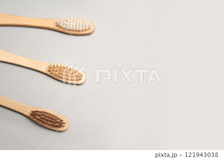 Three eco friendly bamboo toothbrushes with natural bristles on light gray 121943038