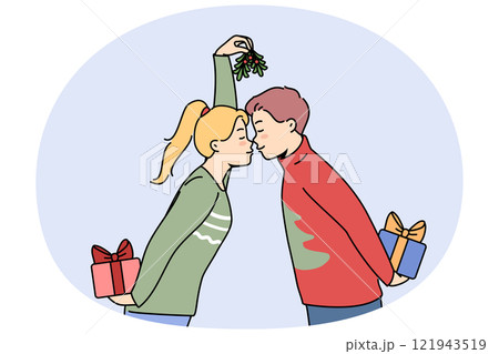 Christmas couple with gift boxes kisses and holds fir cones in hands and exchange new year presents 121943519