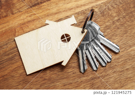 Metal keys with wooden house-shaped keychain on board. Concept of real estate ownership or buying a new home. Top view 121945275