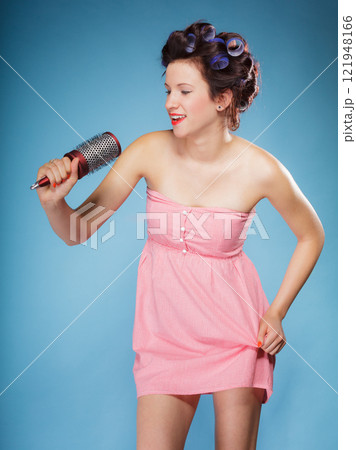 girl with curlers in hair holds hairbrush 121948166