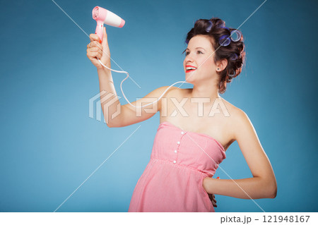 girl with curlers in hair holds hairdreyer 121948167