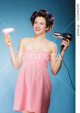 girl with curlers in hair holds hairdreyers 121948169