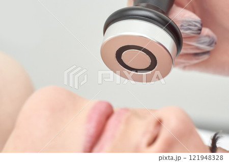 Facial treatment on young caucasian female with modern skincare device 121948328