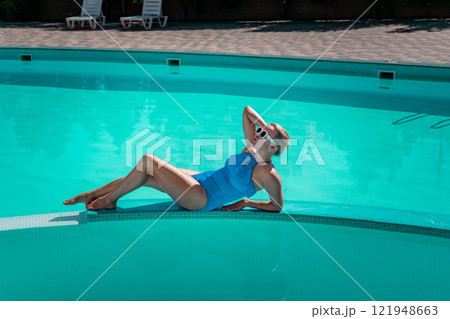 Bikini-clad woman enjoys poolside relaxation. Poolside ambiance. Capturing woman's relaxed time near pool. Bikini-clad woman enjoys poolside relaxation. Poolside ambiance. Capturing woman's relaxed time near pool. 121948663