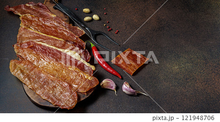 Sliced cured meat on dark background with red chili pepper Sliced cured meat on dark background with red chili pepper 121948706