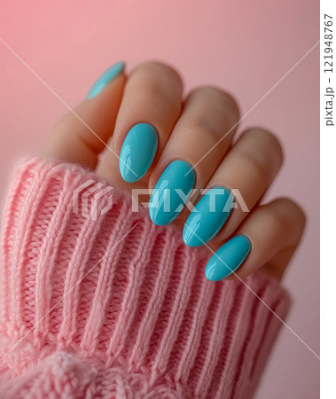 Vibrant turquoise nail polish adorns manicured fingers against a pink background in a cozy setting 121948767