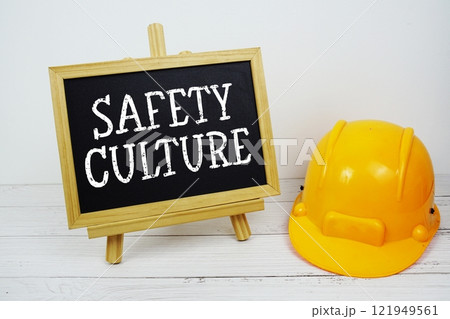 Safety Culture text on blackboard with safety helmet on wooden background 121949561