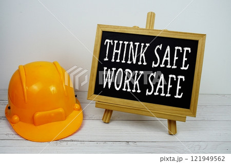 Think Safe Work Safe text on blackboard with safety helmet on wooden background Think Safe Work Safe text on blackboard with safety helmet on wooden background 121949562