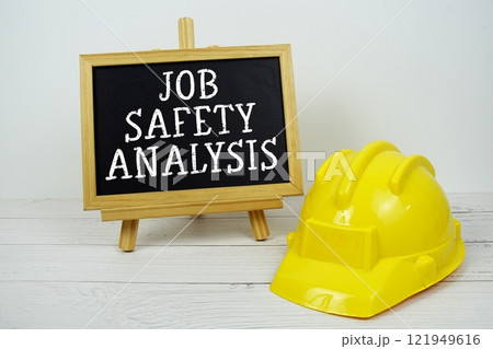 Job Safety Analysis text on blackboard with safety helmet on wooden background 121949616