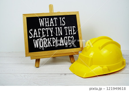 What Is Safety In The Workplace? text on blackboard with safety helmet on wooden background 121949618
