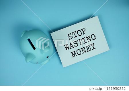 Stop Wasting Money word written on paper card with piggy saving on blue background Stop Wasting Money word written on paper card with piggy saving on blue background 121950232