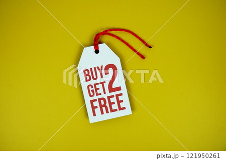 Buy 2 Get 2 Free on price tag with wooden clothes hanger top view on yellow background 121950261
