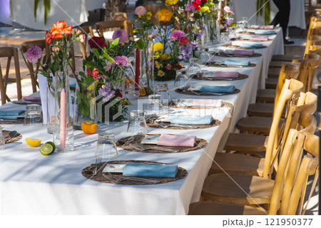 A chilled champagne bottle in ice, elegantly wrapped in a white napkin, stands ready at a luxurious outdoor event by the sea. The background shows gourmet appetizers, enhancing the celebration vibe A chilled champagne bottle in ice, elegantly wrapped in a white napkin, stands ready at a luxurious outdoor event by the sea. The background shows gourmet appetizers, enhancing the celebration vibe 121950377