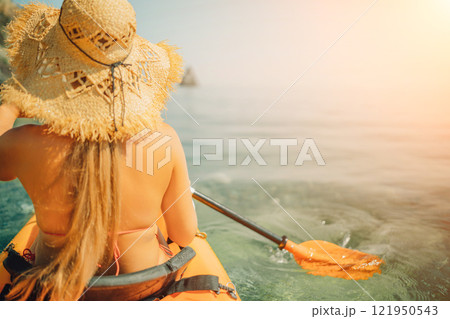 Woman in kayak back view. Happy woman with long hair in a swimsuit and hat floating in kayak on the sea. Summer holiday vacation. Summer holidays vacation at sea. 121950543