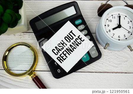 Cash Out Refinance text message on sticky note with magnifying glass, alarm clock and calculator on wooden background 121950561
