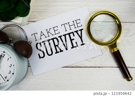 Take The Survey text message with alarm clock and magnifying glass top view on wooden background 121950642