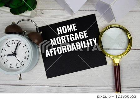 Home Mortgage Affordability text message with house model, alarm clock and magnifying glass top view on wooden background Home Mortgage Affordability text message with house model, alarm clock and magnifying glass top view on wooden background 121950652