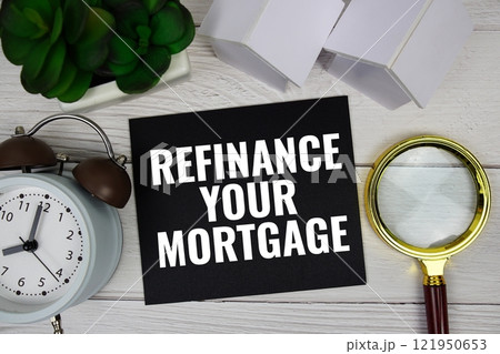 Refinance Your Mortgage text message with house model, alarm clock and magnifying glass top view on wooden background Refinance Your Mortgage text message with house model, alarm clock and magnifying glass top view on wooden background 121950653
