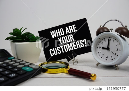 Who Are Your Customers? text message on sticky note with magnifying glass, alarm clock and calculator on wooden background 121950777