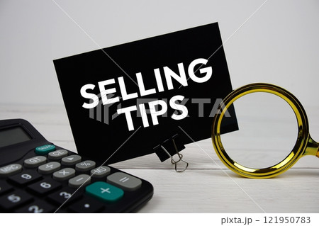 Selling Tips text message on sticky note with magnifying glass and calculator on wooden 121950783