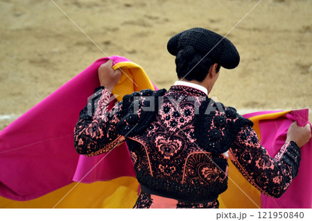 Traditional spanish bullfighter in ornate costume with cape in arena. Tauromaquia. Spanish traditions Traditional spanish bullfighter in ornate costume with cape in arena. Tauromaquia. Spanish traditions 121950840