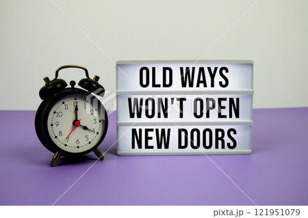 Old Ways Won't Open New Doors text on LED lightbox with alarm clock on purple background 121951079
