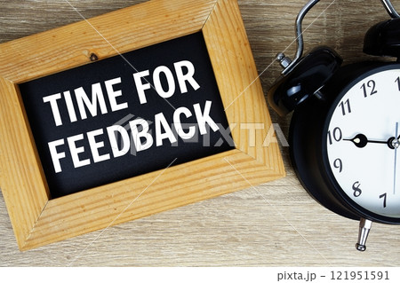 Time for Feedback text on chalkboard with alarm clock top view on wooden background 121951591