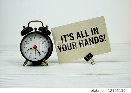 It's all in you hands! text on paper card with alarm clock on wooden background It's all in you hands! text on paper card with alarm clock on wooden background 121951594