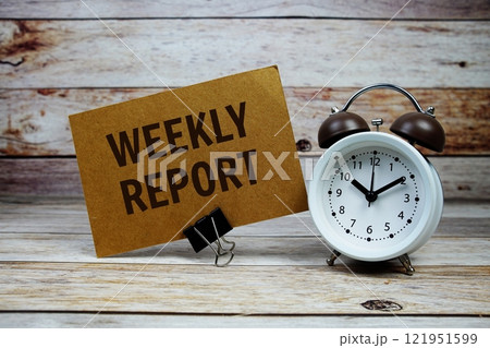Weekly Report text on paper card with alarm clock on wooden background 121951599