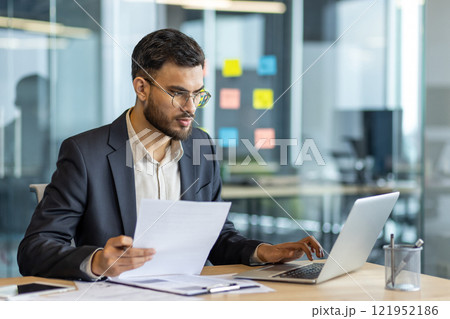 Serious focused businessman at workplace inside office. Man in business suit working with documents and papers, mature successful financier investor reviewing reports. Serious focused businessman at workplace inside office. Man in business suit working with documents and papers, mature successful financier investor reviewing reports. 121952186
