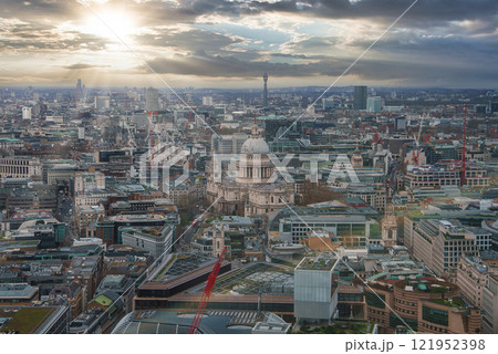 Aerial view of London with St. Paul's Cathedral in the center, surrounded by historic and modern buildings. The sunset casts a warm glow over the city. Aerial view of London with St. Paul's Cathedral in the center, surrounded by historic and modern buildings. The sunset casts a warm glow over the city. 121952398