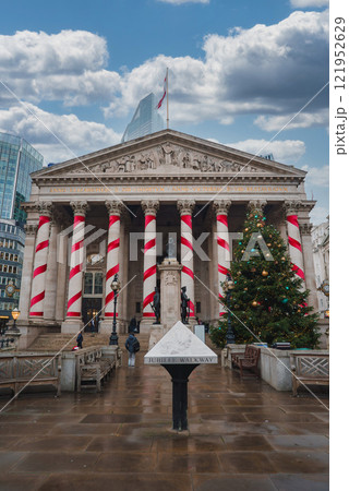 The Royal Exchange in London features festive red and white decorations. A large Christmas tree stands by the entrance, with a modern skyscraper in the background. 121952629