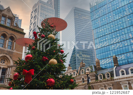 A large Christmas tree with red and gold ornaments stands amid London's modern skyscrapers, including the Leadenhall Building, during the holiday season. 121952687