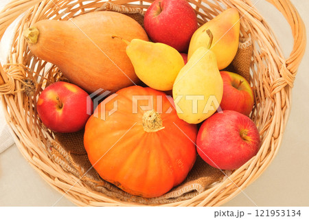 Apples, pears and pumpkins in a straw basket. Orange ripe fruits. Pears, apples and pumpkins are a popular ingredient in cooking. Top view. Apples, pears and pumpkins in a straw basket. Orange ripe fruits. Pears, apples and pumpkins are a popular ingredient in cooking. Top view. 121953134