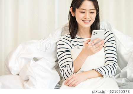 寝室でスマホを見る若い女性 寝室でスマホを見る若い女性 121953578