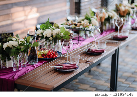 Elegant outdoor table setup with fresh fruit, flowers, and glassware for a festive gathering Elegant outdoor table setup with fresh fruit, flowers, and glassware for a festive gathering 121954149