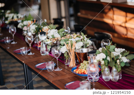 Elegant outdoor table setup with fresh fruit, flowers, and glassware for a festive gathering Elegant outdoor table setup with fresh fruit, flowers, and glassware for a festive gathering 121954150