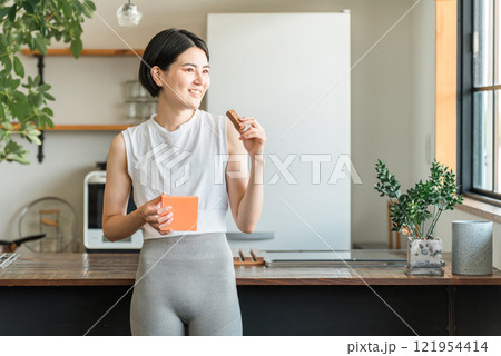 プロテインバー・栄養バーを食べるヨガウェア姿の若いアジア人女性 プロテインバー・栄養バーを食べるヨガウェア姿の若いアジア人女性 121954414