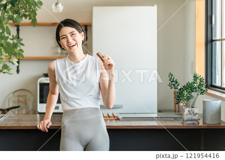 プロテインバー・栄養バーを食べるヨガウェア姿の若いアジア人女性 プロテインバー・栄養バーを食べるヨガウェア姿の若いアジア人女性 121954416