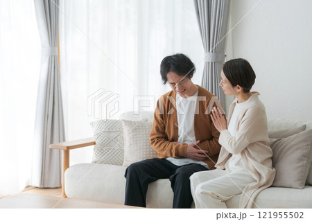 腹痛に苦しむ夫と励ます妻 121955502